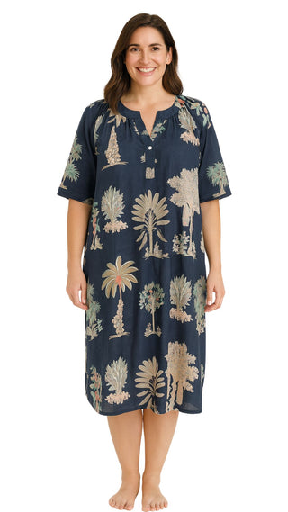 Woman wearing a navy nightie with palm tree pattern on a white background
