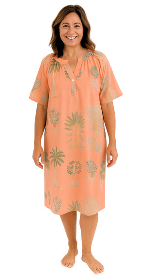 Woman wearing a coral-colored nightie with leaf pattern on a white background